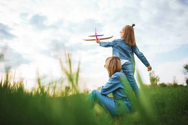 Chica jugando con avión cerca de la madre — Foto de Stock