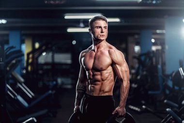 Beyaz yakışıklı fitness modeli spor salonunda poz. Diyet adam kasları esneme ve altı paketi abs
