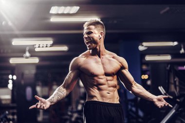 Beyaz yakışıklı fitness modeli spor salonunda poz. Diyet adam kasları esneme ve altı paketi abs