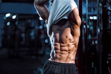 Beyaz yakışıklı fitness modeli spor salonunda poz. Diyet adam kasları esneme ve altı paketi abs