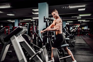 Arka üstünde makine için ağır egzersiz yaparak güçlü vücut geliştirmeci