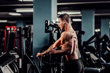 Arka üstünde makine için ağır egzersiz yaparak güçlü vücut geliştirmeci