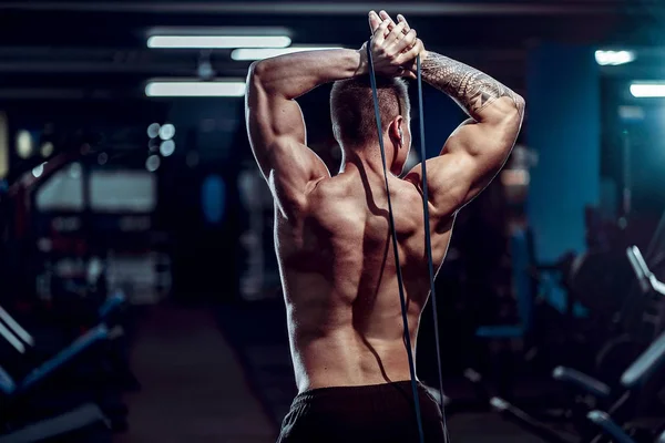 Trabajar duro deportista bien construido haciendo ejercicio con una banda de resistencia — Foto de Stock