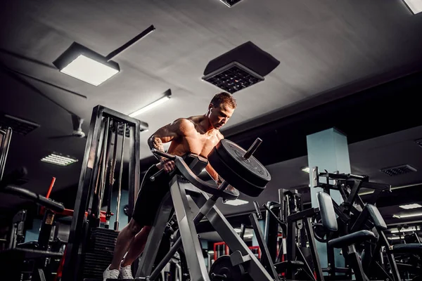 Culturista fuerte haciendo ejercicio de peso pesado para volver a la máquina. Ejercicio T-pull — Foto de Stock