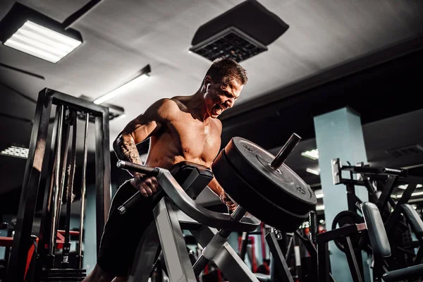 Culturista fuerte haciendo ejercicio de peso pesado para volver a la máquina. Ejercicio T-pull — Foto de Stock