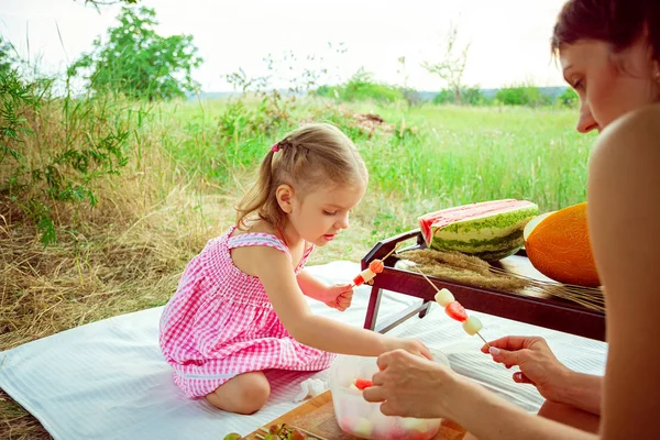 Duas garotas sorridentes comem fatia de melancia ao ar livre no prado. Mãe e filha passam o tempo juntas — Fotografia de Stock
