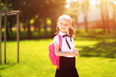 Sırt çantalı güzel bir kız. Parkta yürüyor. Okula geri dönüyor.