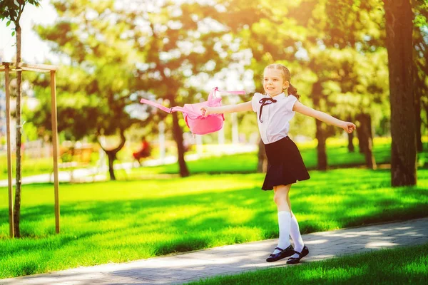 Retrato de una joven caucásica feliz que sonríe con una mochila escolar fuera de la escuela primaria. Un chico después de las clases se va a casa. Fin del estudio. Verano — Foto de Stock