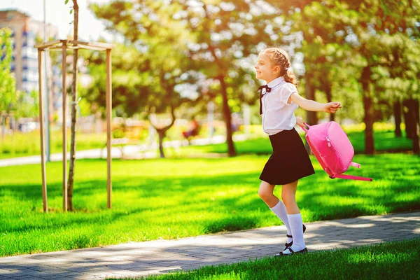 Retrato de una joven caucásica feliz que sonríe con una mochila escolar fuera de la escuela primaria. Un chico después de las clases se va a casa. Fin del estudio. Verano — Foto de Stock