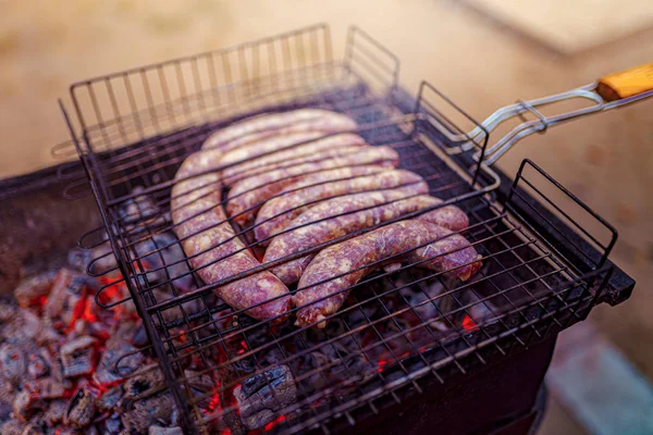 Surowe kiełbasa grillowane na piknik Flaming Grill — Zdjęcie stockowe