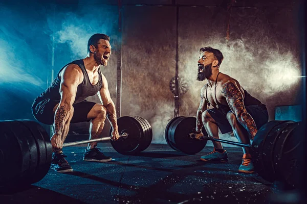 Dois atletas musculosos tatuados treinando no ginásio — Fotografia de Stock