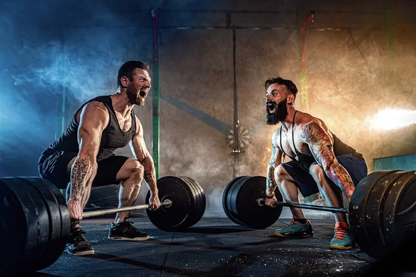 Zwei muskulöse bärtige tätowierte Athleten beim Training im Fitnessstudio — Stockfoto