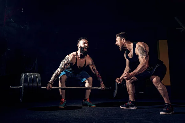 Twee gespierde baard getatoeëerde atleten trainen in de sportschool — Stockfoto