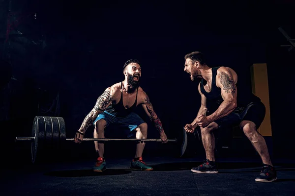 Zwei muskulöse bärtige tätowierte Athleten beim Training im Fitnessstudio — Stockfoto