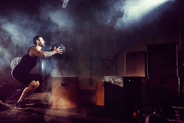 Athlete gave exercise. Jumping on the box. Phase touchdown. Gym shots in the dark tone. Smoke. — Stock Photo, Image
