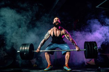 Modern fitness merkezinde kaslı bir fitness adamı halterle kafasına halteri indiriyor. Fonksiyonel eğitim.