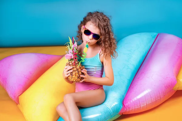 Beautiful girl in colorful swimsuit and sunglasses holding pineapple cocktail — Stock Photo, Image