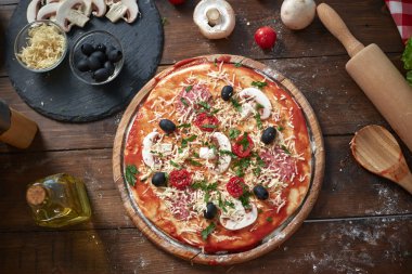 Ahşap tahta üzerinde ev yapımı pizza, domates ve salam, mantar, eski ahşap masada Italyan tarzı, üst görünüm