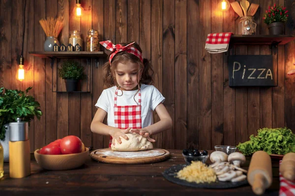 漂亮的女孩在方格围裙揉面包面团比萨饼 — 图库照片