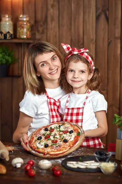 Happy Smiling mother and daughter with cooked pizza