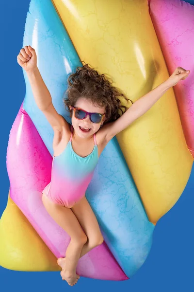 Piękna dziewczynka w kolorowym stroju kąpielowym i okularach przeciwsłonecznych leży, zrelaksować się na materacu — Zdjęcie stockowe