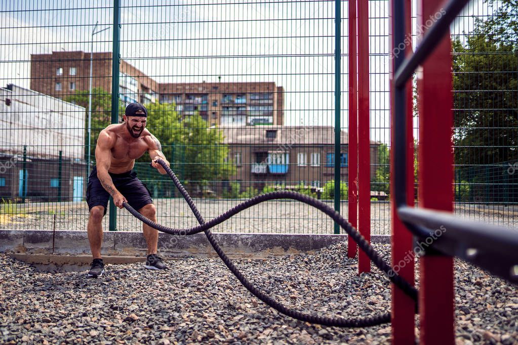 Men work hard with rope, functional training