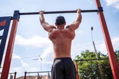 Acımasız atletik adam bir crossbar üzerinde pull-up egzersizleri yapma.