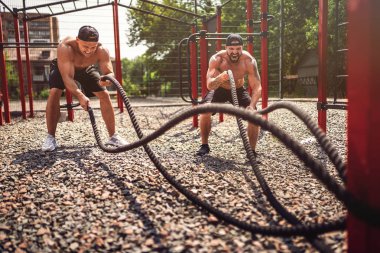 Erkekler sokak spor salonunda ip ile çok çalışırlar. Güç ve motivasyon. Açık hava egzersizi. fitness, spor, egzersiz, eğitim ve yaşam tarzı kavramı .