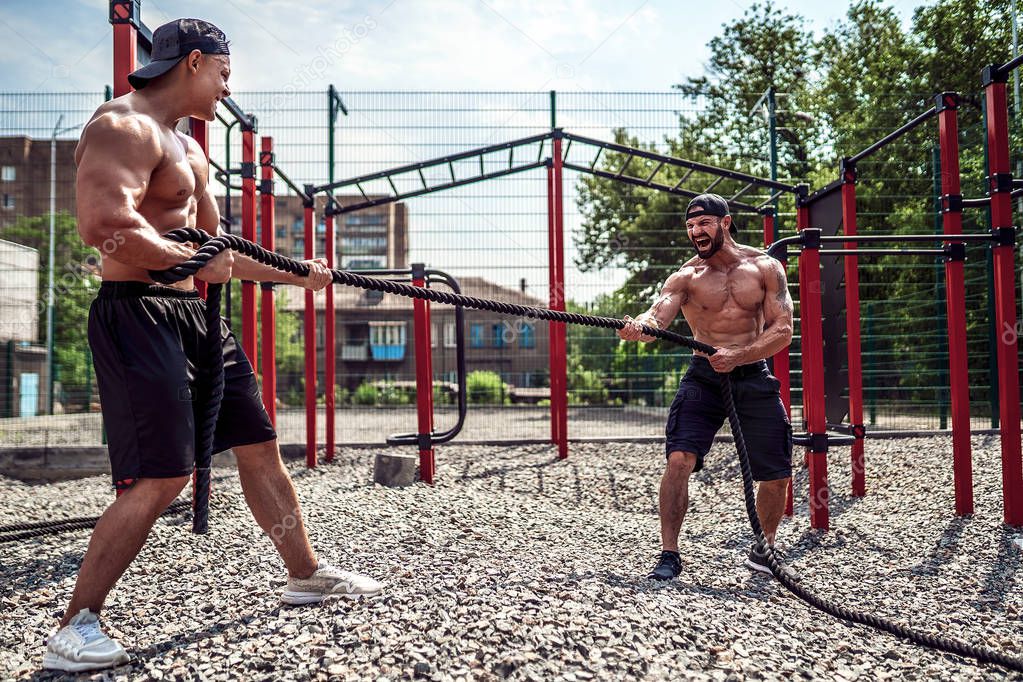 Men work hard with rope at street gym yard. Strength and motivation. Outdoor workout. fitness, sport, exercising, training and lifestyle concept .