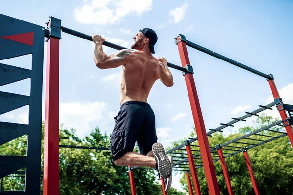 Brutaler athletischer Mann macht Klimmzug-Übungen an der Querlatte. — Stockfoto