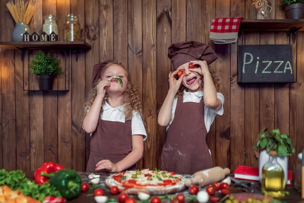 Filles drôles cuisine pizza et duper avec des tomates et de la laitue — Photo