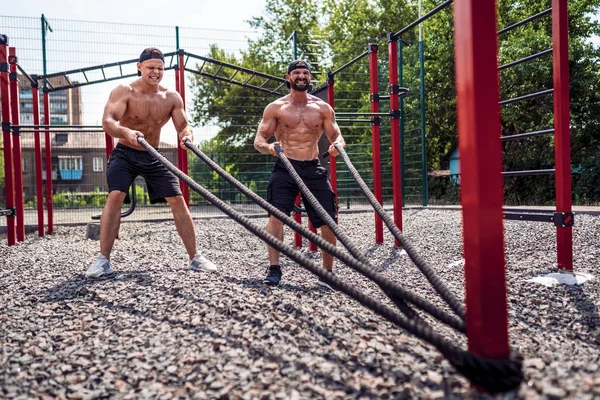 Männer arbeiten auf dem Hof der Turnhalle hart mit Seilen. Stärke und Motivation. Outdoor-Training. Fitness, Sport, Bewegung, Training und Lifestylekonzept . — Stockfoto