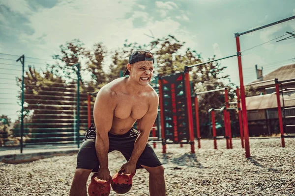 Атлетик тренируется с гирей во дворе спортзала на улице. Сила и мотивация . — стоковое фото