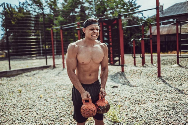 Атлетик тренируется с гирей во дворе спортзала на улице. Сила и мотивация . — стоковое фото