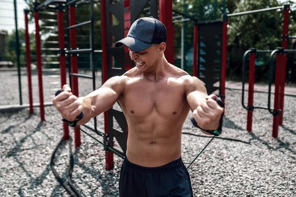 Fitness man exercising with stretching band in outdoor gym.