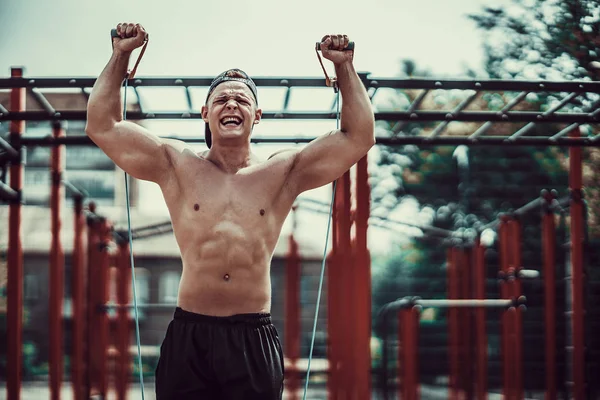 Fitness man exercising with stretching band in outdoor gym. — Stock Photo, Image