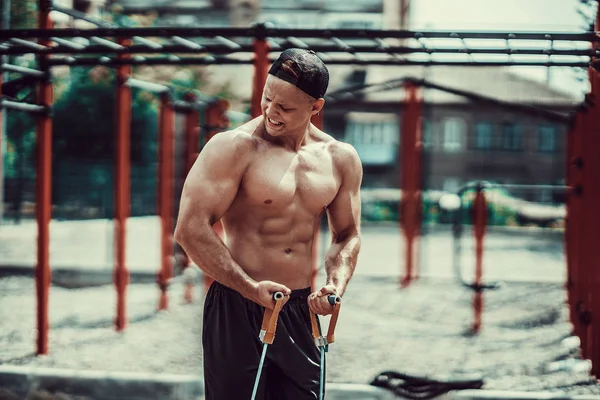 Fitness man exercising with stretching band in outdoor gym.