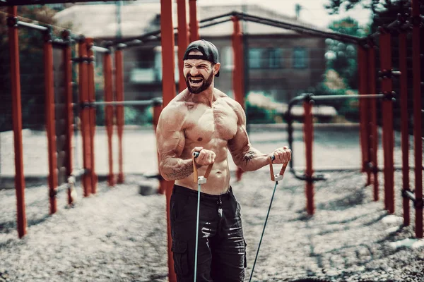 Fitness man exercising with stretching band in outdoor gym. — Stock Photo, Image