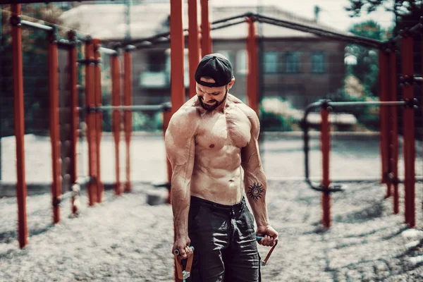 Fitness man exercising with stretching band in outdoor gym.