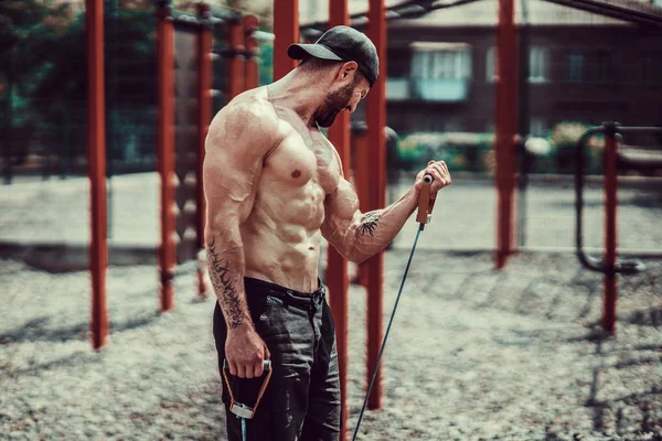 Fitness man die traint met stretching band in outdoor gym. — Stockfoto