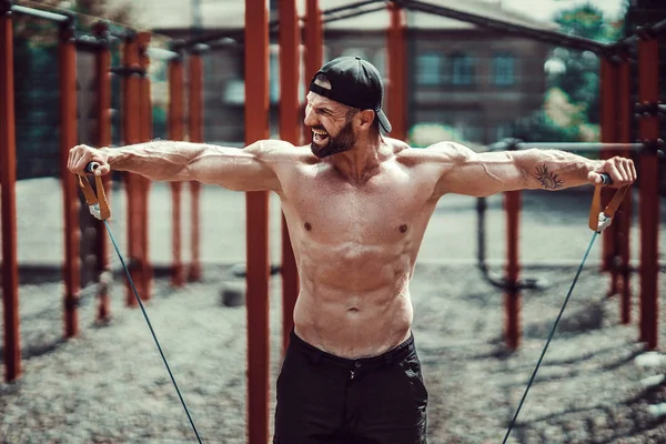 Fitness man exercising with stretching band in outdoor gym. — Stock Photo, Image