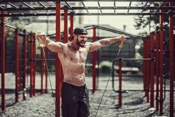 Homem de fitness exercitando com banda de alongamento no ginásio ao ar livre . — Fotografia de Stock