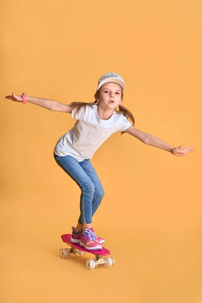 노란색 배경을 통해 스케이트 보드캐주얼 세련된 어린 소녀 소녀 소녀 — 스톡 사진