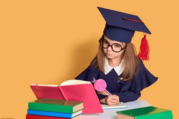 Neugierige Schülerin im Abschlussoutfit studiert mit Lehrbüchern — Stockfoto