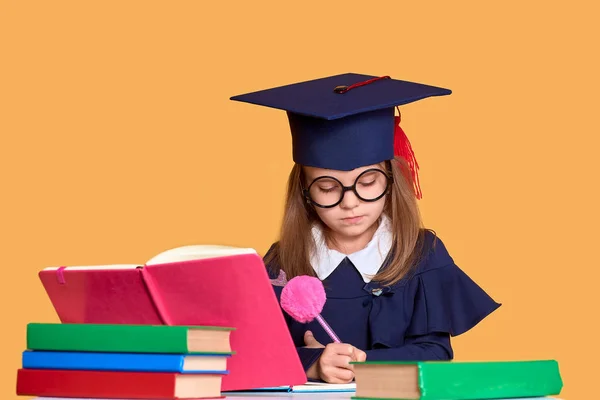 Neugierige Schülerin im Abschlussoutfit studiert mit Lehrbüchern — Stockfoto