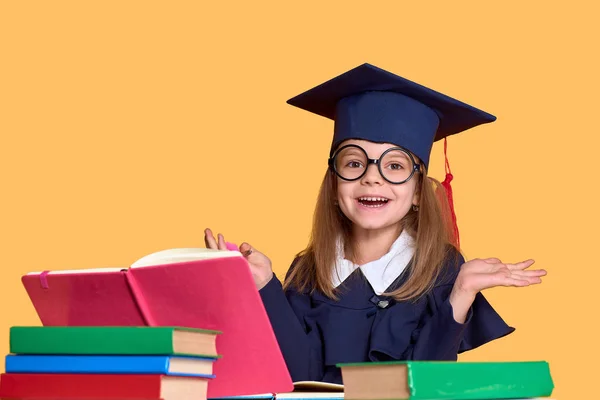 Opgewonden schoolmeisje in afstuderen outfit studeren met studieboeken — Stockfoto