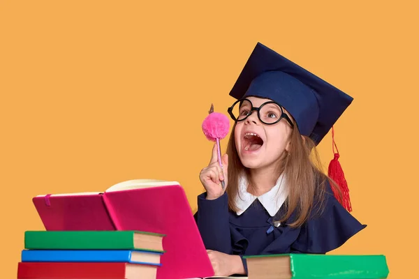 Opgewonden schoolmeisje in afstuderen outfit studeren met studieboeken — Stockfoto