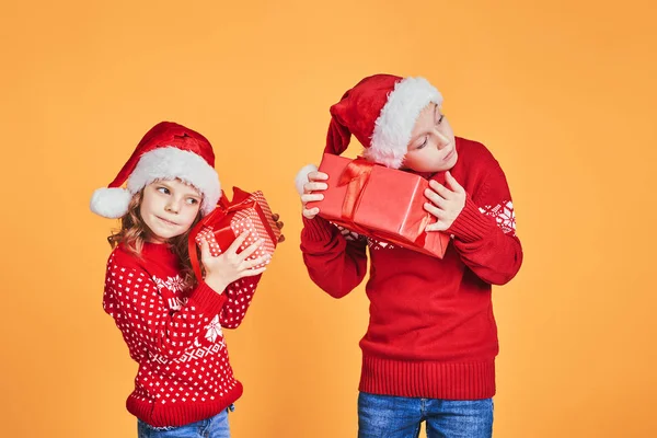 Kırmızı hediye kutularını tutan mutlu çocuklar.