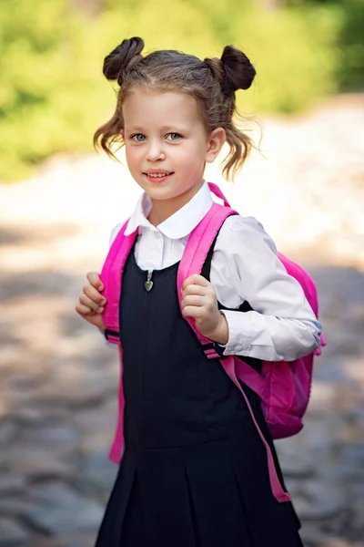 학교 배낭을 입고 웃는 학생 소녀입니다. 초등학교 밖에서 행복한 백인 소녀의 초상화입니다. 카메라를 보고 웃는 여학생. — 스톡 사진