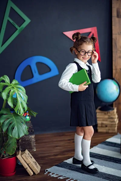 Menina inteligente com livro didático na escola — Fotografia de Stock